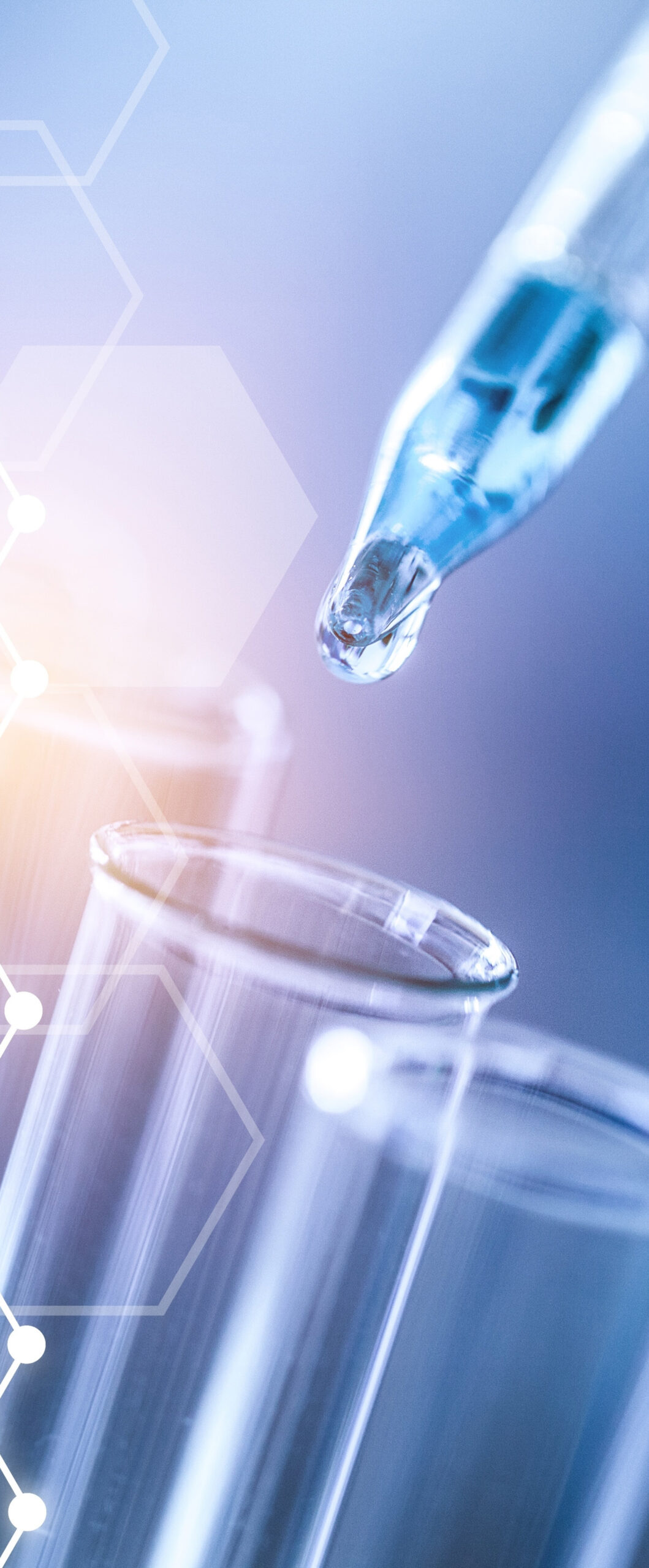 Close-up of a pipette dispensing liquid into a test tube, with hexagonal patterns and a blue-orange gradient backdrop.